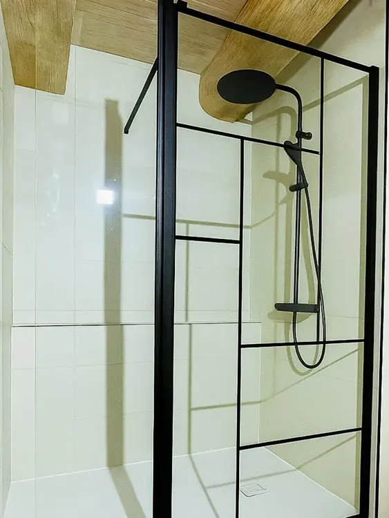 Receveur extra-plat, robinetterie noire et paroi verrière : cette configuration séduit de nombreux propriétaires souhaitant remplacer leur baignoire et gagner en confort au quotidien. Intervention sur Sanary-sur-Mer, Bandol, Six-Fours-les-Plages et l'agglomération toulonnaise. Douche contemporaine avec paroi verrière noire, receveur extra-plat et robinetterie noire mate