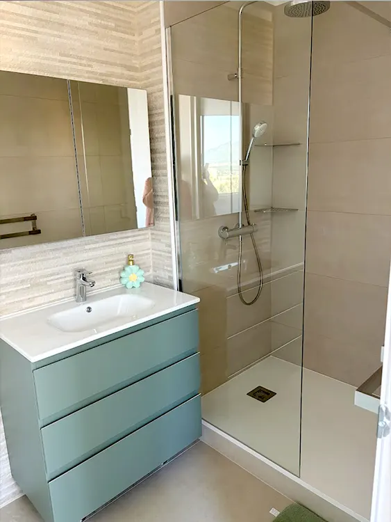 Aménagement complet d'un espace réduit avec douche confortable, meuble vasque compact et circulation améliorée. Une solution idéale pour moderniser une salle de bain tout en conservant un maximum de fonctionnalité. Petite salle de bain rénovée avec douche ouverte et meuble vasque vert à Sanary-sur-Mer par Grech Salle de Bain