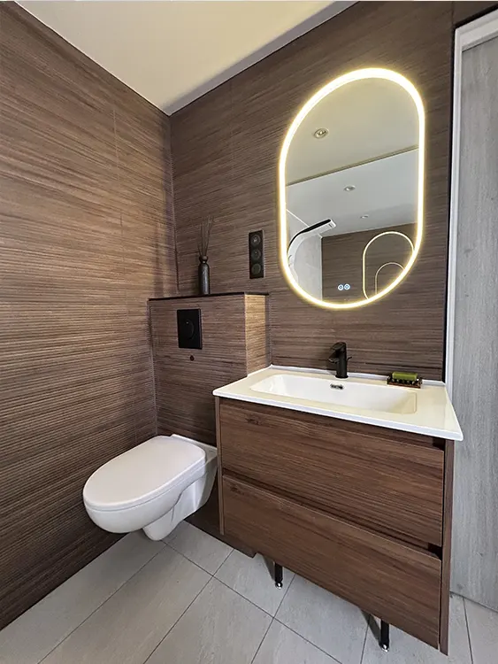 Espace toilette contemporain avec meuble vasque effet bois, miroir LED rétroéclairé, robinetterie noire et WC suspendu à Sanary-sur-Mer. Meuble vasque en bois et miroir rétroéclairé